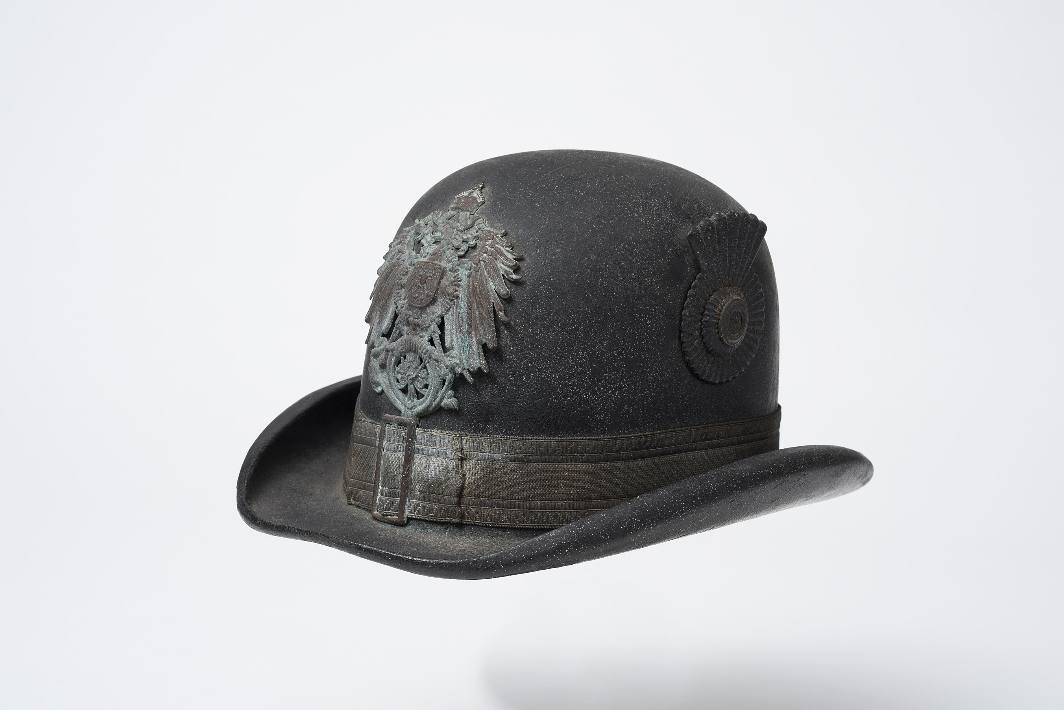 Ende des 19. Jahrhunderts, Herkunft unbekannt, Lederkorpus mit Krempe, Tressenband mit Schnalle, Reichsadler mit dem Posthorn (Emblem der Deutschen Reichspost [1871– 1919]), farbig lackierte Landeskokarde, innen: Schweißleder, Filz (Regenschutz), Sammlung: museum oder-spree (Foto: Bernd Choritz)